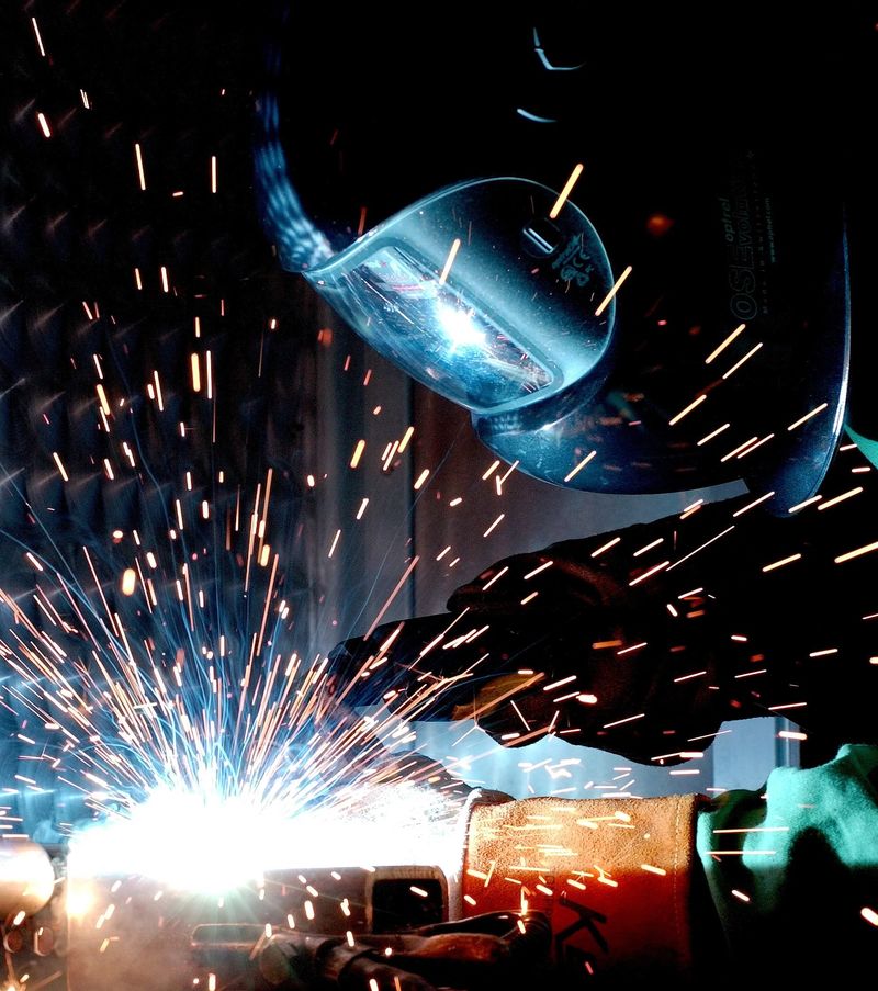 Close-up of MIG welding with bright sparks and protective visor